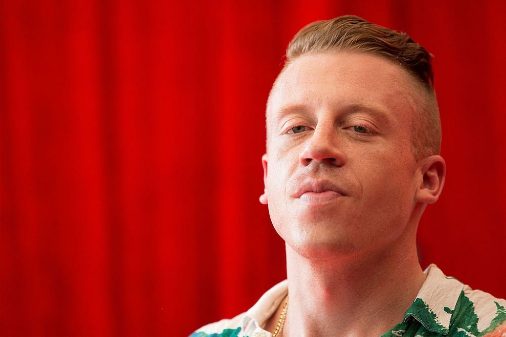 Macklemore, de nerecunoscut. Are părul lung și poartă mustață